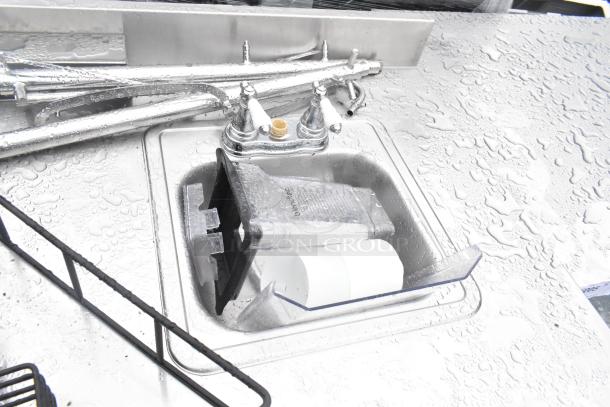 Stainless steel commercial table with a single bay sink, metal under shelf, clean condition, includes faucet and drain fittings.