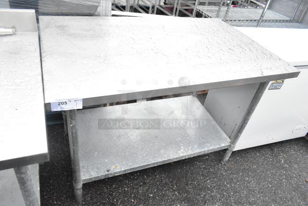 Stainless steel table with under shelf, industrial design, sturdy legs, visible wear, suitable for kitchen or restaurant use.