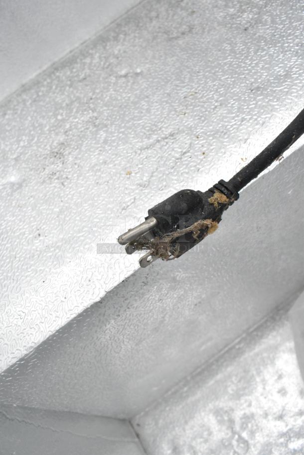 Avantco 178HF5 metal chest freezer power cord, 115 volts, 1 phase, showing signs of wear and debris accumulation.