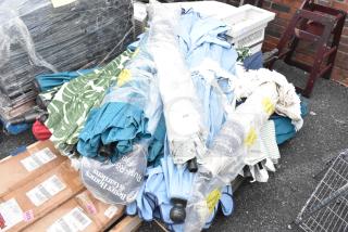 Pallet of assorted items including colorful patio umbrellas, some wrapped in plastic. Visible labels and packaging intact.