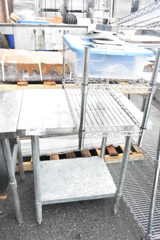 Stainless steel table with metal under shelf, includes wire shelving unit and plastic container; good condition.