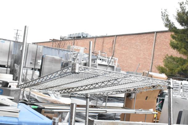 Chrome finish 4-tier wire shelving unit in outdoor setting. Buyer must dismantle. Consider freight charges.