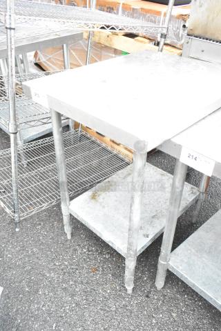 Stainless steel table with metal under shelf, sturdy construction, visible wear, ideal for industrial use.