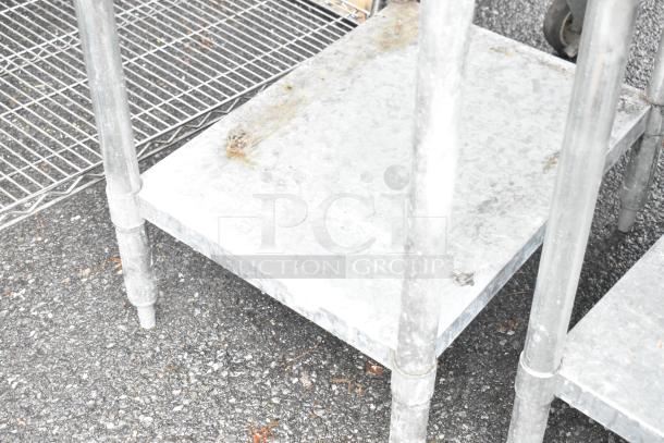 Stainless steel table with a metal under shelf, visible rust and wear, suitable for industrial use.
