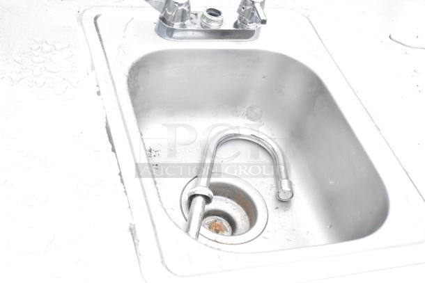 Stainless steel table with single bay sink; features metal under shelf. Faucet visible. Shows moderate wear.