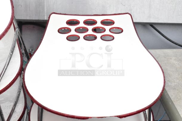 Five white stools with unique red-trimmed seats and chrome finish legs, modern design; minor wear visible.