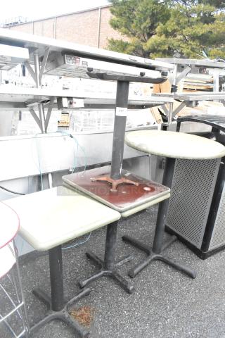 Four various tables, including three dining height and one bar height, with metal bases, showing signs of wear. Label "217" visible.