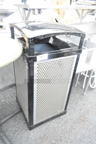Rubbermaid black metal trash can shell with perforated sides. Prominent top opening, minor wear. Label marked "218" visible.