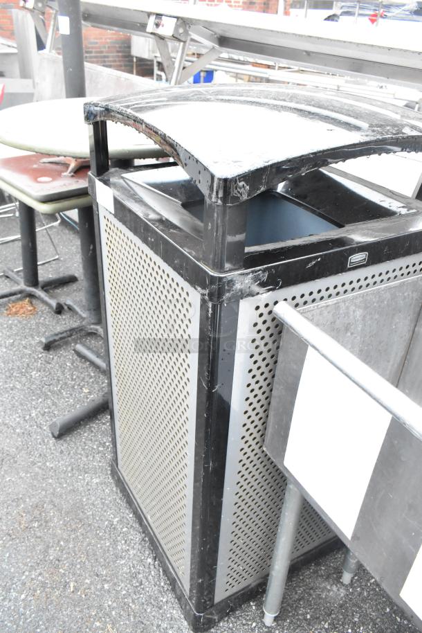 Rubbermaid black metal trash can shell, perforated design, outdoor use, fair condition, some surface wear visible.