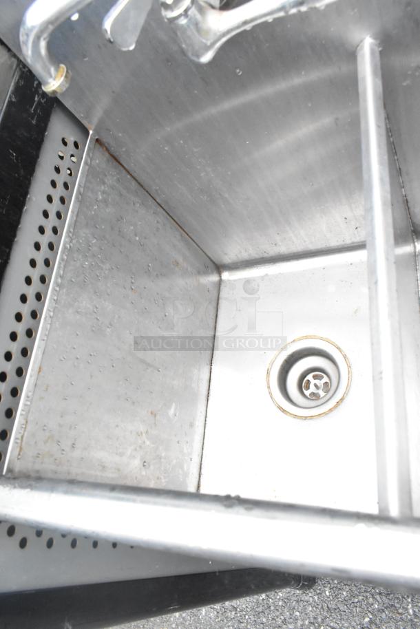 Stainless steel 2 bay sink with faucet and handles, showing drain and slight wear. Ideal for commercial use.