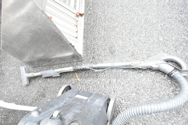 Kenmore 116.23313302 Vacuum Cleaner, shown on pavement, features hose and handle. Some wear visible, 120 Volts, 1 Phase.