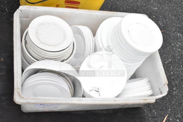 Lot of white ceramic plates in poly white bin; various sizes, used condition, suitable for bulk purchase.