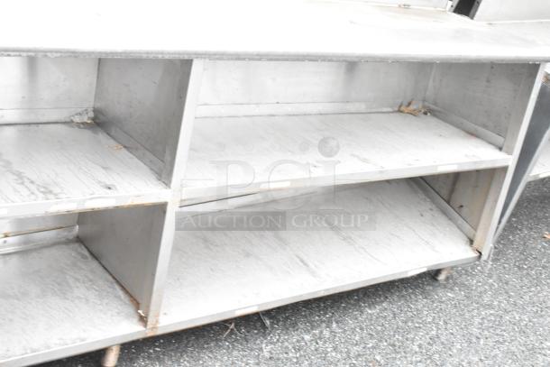 Stainless steel commercial table with two food strip warmers, under shelves, and over shelves. Visible wear on surfaces.
