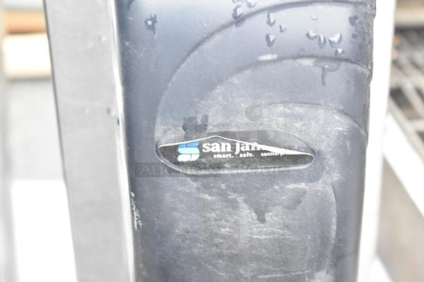 San Jamar poly soap dispenser on a metal stand, visible wear, company logo, slogan "smart. safe. sanitary."