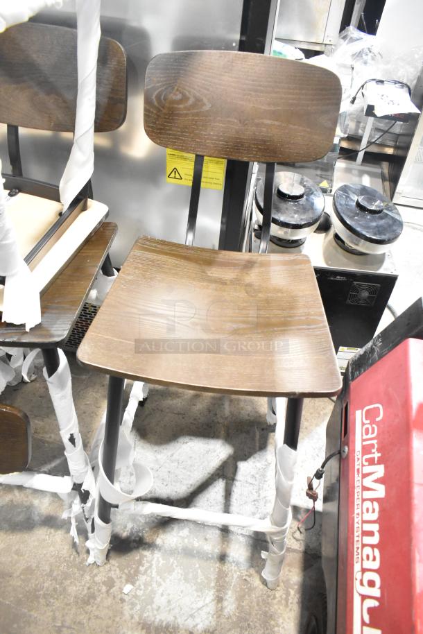 Black metal bar height chair with wooden seat and backrest, brand new with minor scratches and dents, protective wrapping visible.