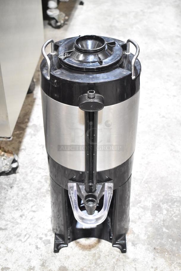 Fetco Stainless Steel Beverage Holder Dispenser, cylindrical design, black and silver finish, with spout and carrying handles.
