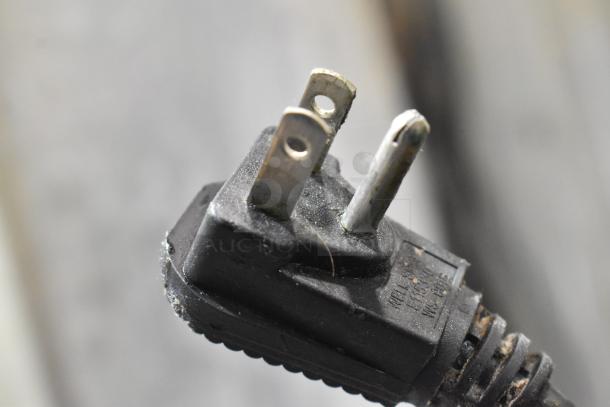 Close-up of a two-prong power plug connected to the Continental 1R-HD Reach In Cooler, showing wear and slight rust.