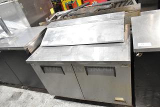 True TSSU-48-12 stainless steel sandwich prep table with hinged lid and visible wear. Mega top, on casters, 115V, 1 phase.