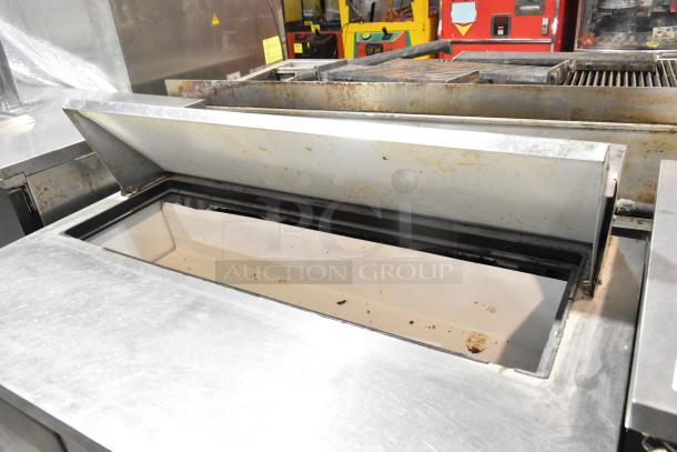 True TSSU-48-12 stainless steel sandwich salad prep table with open lid, showing interior. Features commercial casters.