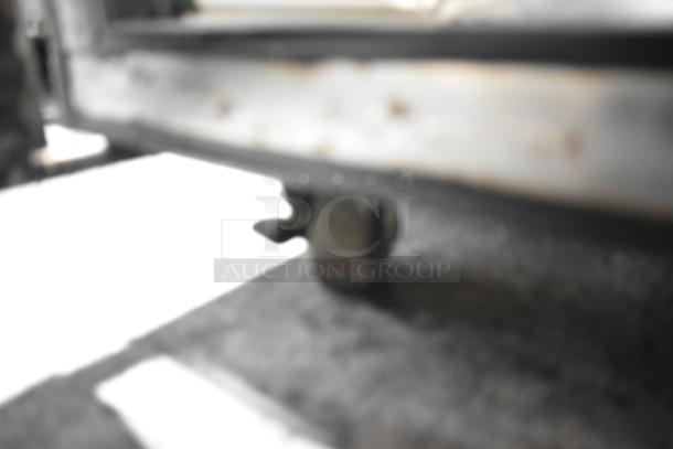 Blurred image showing a commercial caster under a True TSSU-48-12 stainless steel sandwich prep table.