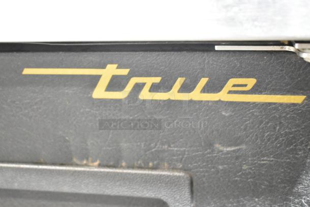 True TDB-24-48 kegerator logo detail. Black metal with gold lettering. Suitable for commercial use.