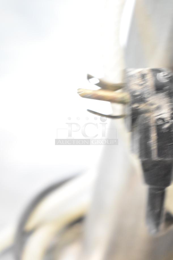 Blurry image of a metallic object with protruding cylindrical elements, possibly from the True TDB-24-48 kegerator.
