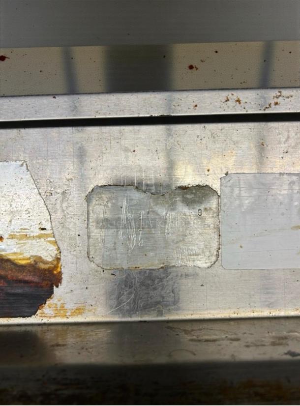 Close-up of a used metal surface with visible rust and wear, part of a Jade Range 36" commercial gas range.