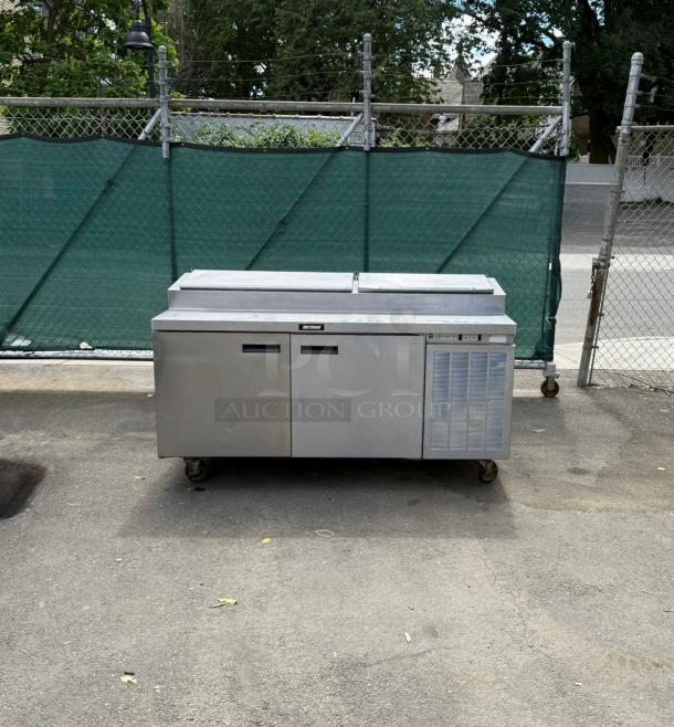 Delfield 18672PTLP 72" refrigerated pizza prep table, two doors, raised rail, stainless steel, visible wear, on wheels.