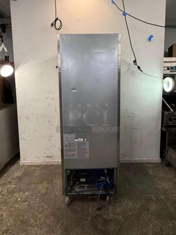DUKERS D28R single-door commercial refrigerator, stainless steel, visible wear and dents, informational labels, on casters.