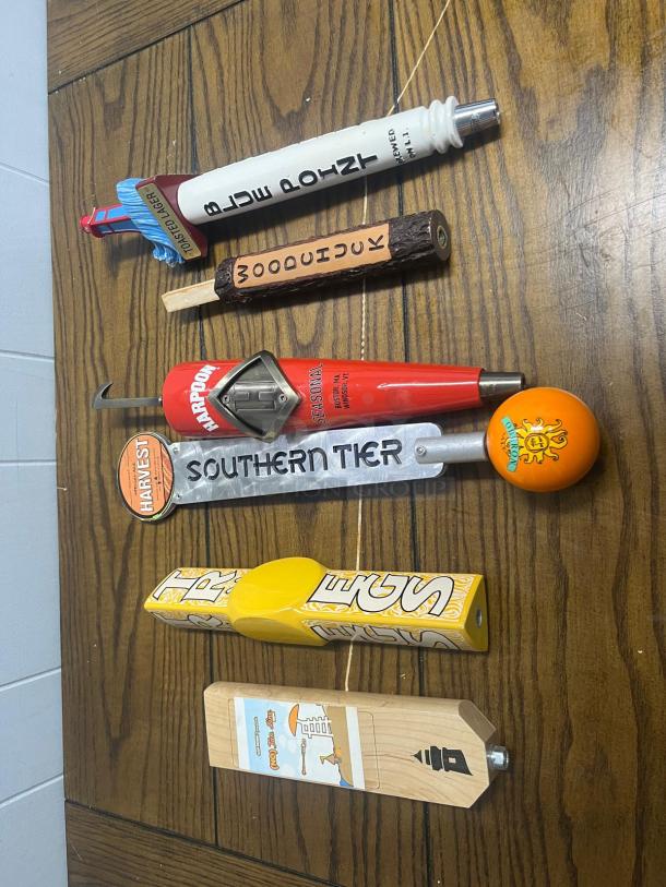 Assorted tap handles featuring various designs and brands, including Harpoon and Southern Tier, in good condition.