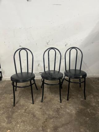 Three cafe dining chairs with black metal frames, padded vinyl seats. Used condition with visible wear on seats.