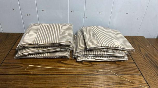 Brand new striped aprons, neatly folded and packaged, displayed on a wooden surface.