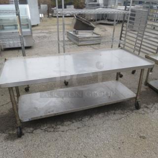 Stainless steel table with under shelf on casters, measuring 72x28.5x30 inches. Good condition, ideal for commercial use.
