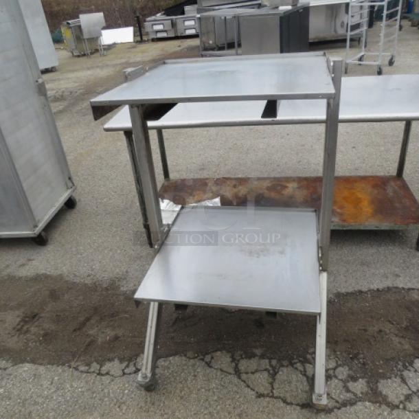 Stainless steel two-shelf work table on casters, measures 28x26x47.5 inches, used condition.