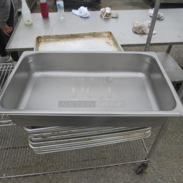 Stainless steel full-size 4-inch deep hotel pan, used, on metal rack. No visible tags or markings.