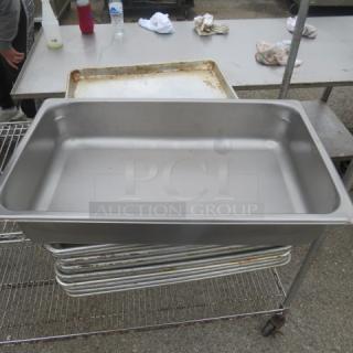 Stainless steel full-size 4-inch deep hotel pan, used, on metal rack. No visible tags or markings.