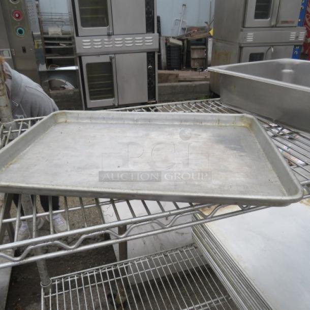 Aluminum 1/2 size sheet pan on metal rack, showing signs of wear. Ideal for baking or roasting.