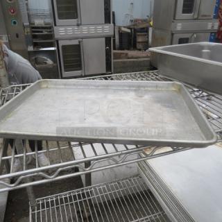 Aluminum 1/2 size sheet pan on metal rack, showing signs of wear. Ideal for baking or roasting.