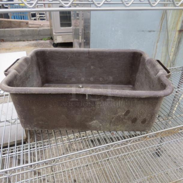 Brown plastic bussing tub with handles, signs of wear, placed on a metal rack. Durable for commercial use.