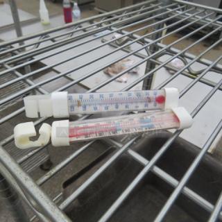 Assorted thermometers on metal rack; two glass models with marked temperature scales in Celsius, plastic ends, used condition.
