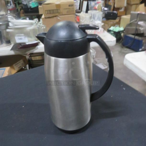Stainless steel Adcraft creamer with black plastic lid and handle, excellent condition, used for dispensing cream.