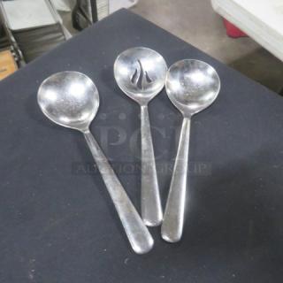 Assorted stainless steel spoons, set of 3. One spoon features slotted design. Minor wear visible, in good condition.