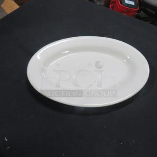 White 12.5x9 oval platter, ceramic, in good condition, resting on a dark surface. No visible markings or labels.