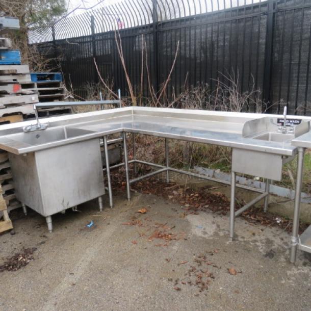 Stainless steel work table with handsink 10x14x8 and large deep sink 28x28x28, both with faucets. Dimensions 81x105x40.5. Potential outdoor element exposure.