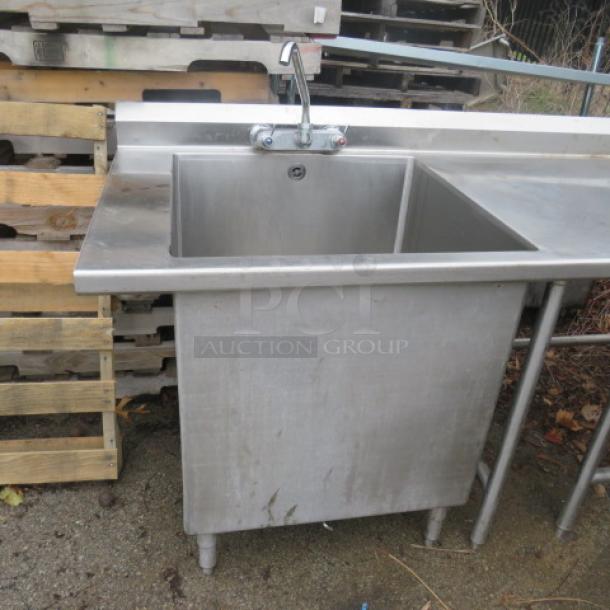 Stainless steel work table with 10x14x8 hand sink and 28x28x28 deep sink, both with faucets. Dimensions: 81x105x40.5 inches.