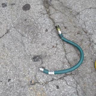 Green gas line hose with metal fittings, slightly worn, label reads "REGUL"; suitable for connecting gas appliances.