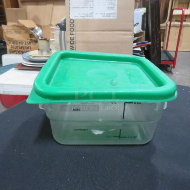 2-quart food storage container with green lid, transparent body marked with measurements, used in kitchen settings.