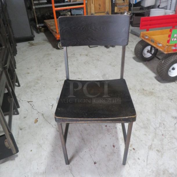 Black wooden chair with metal frame, showing signs of wear on seat edges, simple design.