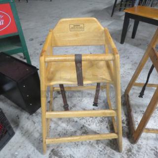 Wooden high chair with safety straps, natural finish, used condition. Features safety warning label. Ideal for dining use.