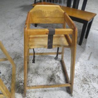 Wooden high chair with safety straps, shows wear; suitable for vintage decor or functional use.